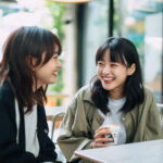 カフェ内で同級生と笑顔で会話する女の子