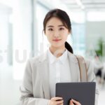 社内でタブレットを手に立つ彼女