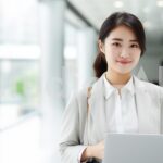 社内でタブレットを手に立つ彼女